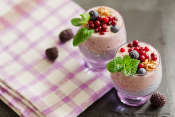 Layered chia, banana and berry smoothie garnished with fresh  mint, healthy food style on black slate background