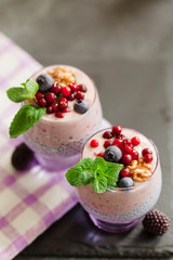 Layered chia, banana and berry smoothie garnished with fresh  mint, healthy food style on black slate background