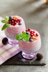Layered chia, banana and berry smoothie garnished with fresh  mint, healthy food style on black slate background