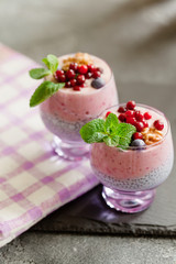 Layered chia, banana and berry smoothie garnished with fresh  mint, healthy food style on black slate background