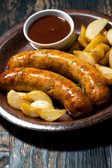 fried pork sausages with potatoes and ketchup, vertical closeup