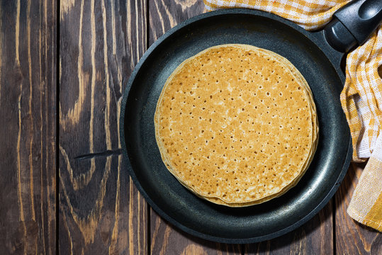traditional thin pancakes in a frying pan, top view