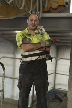 Construction worker man with non-stick liquid tank for industrial concrete mixers poses looking at camera. Real people in their work environment.