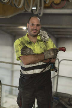Construction worker man with non-stick liquid tank for industrial concrete mixers poses looking at camera. Real people in their work environment.