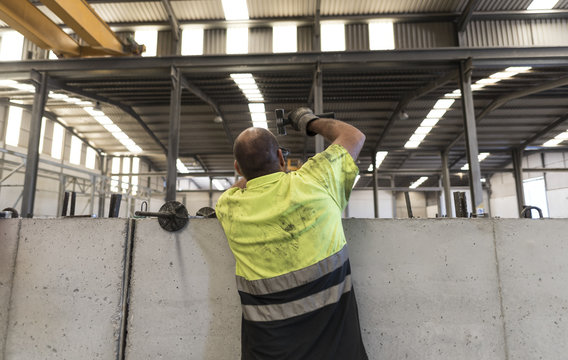 Man hammering concrete structures in construction plant factory
