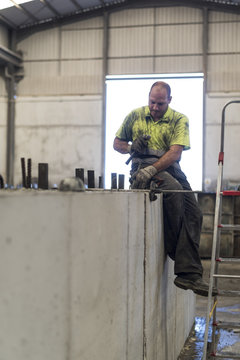 Worker with chisel sculpts the newly made concrete structure to introduce metal grabs