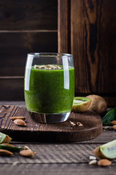 Detox Dieting, Clean Eating Vegan Drink Concept. Fresh Green juices or smoothies in glass with kiwi, banana, spinach and nut almond on wooden board table background.  Copy space.
