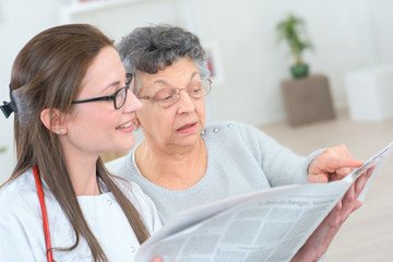 carer and old lady checking something in newspaper
