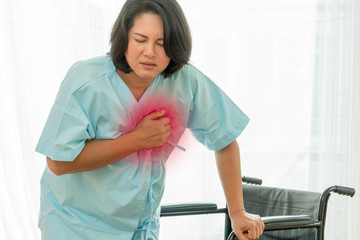 Middle aged asian lady with heart attack. Chubby woman grabbing at her breast have a heart attack and need emergency help.