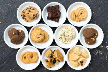 Cookies and brownie in white ceramic container flat lay on table top, Top view different cookies in white bowl