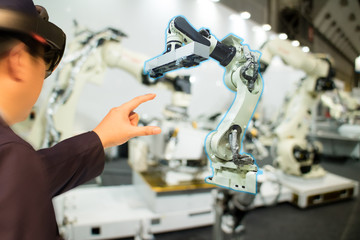 iot industry 4.0 concept,industrial engineer(blurred) using smart glasses with augmented mixed with virtual reality technology to monitoring machine in real time.Smart factory use Automation robot arm