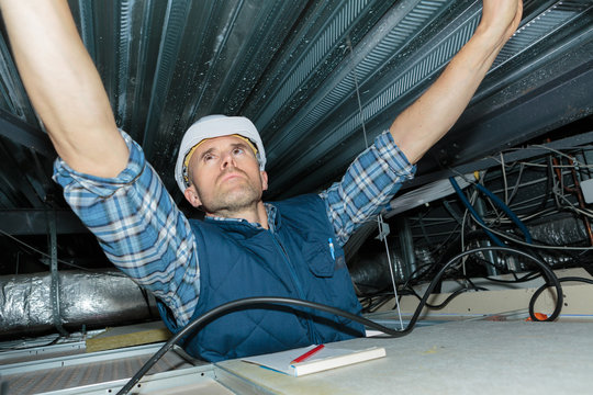 man repairing electrical wiring on the ceiling