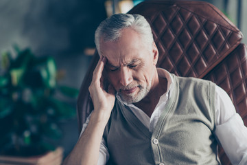 Close up portrait of sad upset nervous troubled problematic entrepreneur having strong headache wearing knitted waistcoat white shirt touching head temples with closed eyes