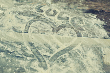 heart painted with finger on flour close-up