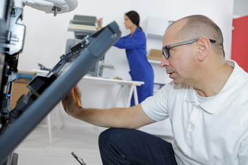 specialist technician repairs a photocopier in a business office