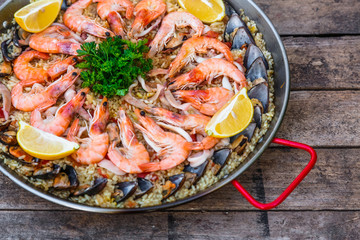 Traditional seafood paella in the fry pan on a wooden old table, top view