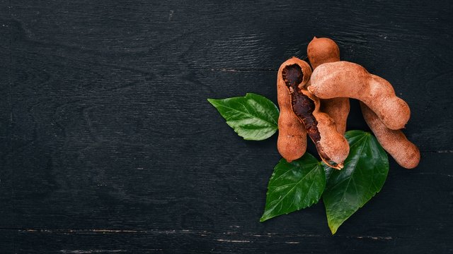 Tamarind. Tropical Fruits. On a wooden background. Top view. Copy space.