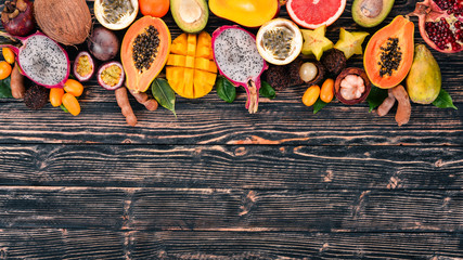Tropical fruits, papaya, Dragon Fruit, rambutan, tamarind, cactus fruit, avocado, granadilla, carambola, kumquat, mango, mangosteen, passionfruit, coconut. On a wooden background.