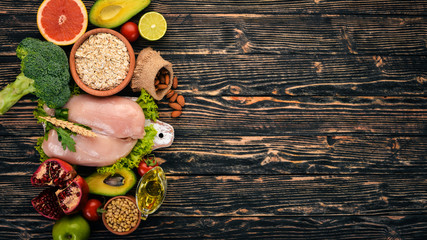 Healthy food. Chicken fillet, avocado, broccoli, fresh vegetables, nuts and fruits. On a wooden background. Top view. Copy space.