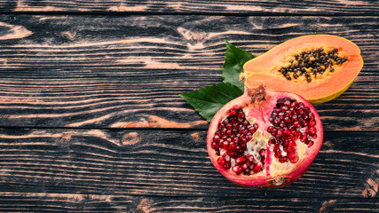 Pomegranate fruit and papaya. Tropical Fruits. On a wooden background. Top view. Copy space.