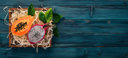 Papaya and Dragon Fruit. Fresh Tropical Fruits. On a wooden background. Top view. Copy space.