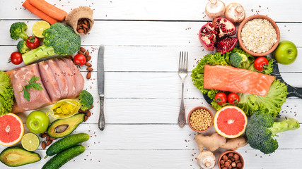 Healthy food background. Concept of Healthy Food, Chicken Fillet, Raw Meat, Fish, Avocado, Broccoli, Fresh Vegetables, Nuts and Fruits. On a wooden background. Top view. Copy space.