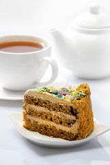 cake on background of cup with tea and teapot