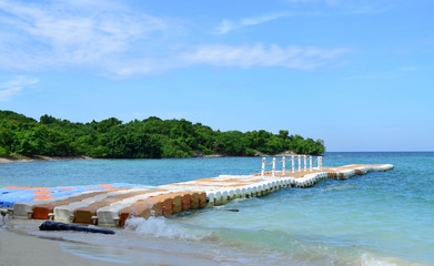Line of plastic pier on blue sea with green island