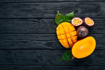 Mango and passion fruit. Fresh Tropical Fruits. On a wooden background. Top view. Copy space.