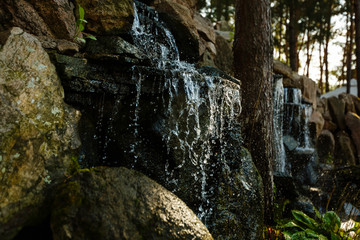 Fototapeta na wymiar Close up of water splashing on rocks from a waterfall Water on decorative stones