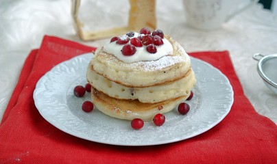 Appetizing berry pancakes with sour cream sauce and powdered sugar