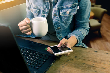Young Asia woman using laptop and smartphone while holding cup of coffee. Business and Technology with modern lifestyle concept.