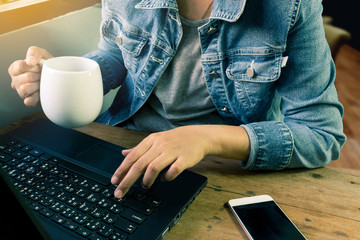 Young Asia woman using laptop and smartphone while holding cup of coffee. Business and Technology with modern lifestyle concept.