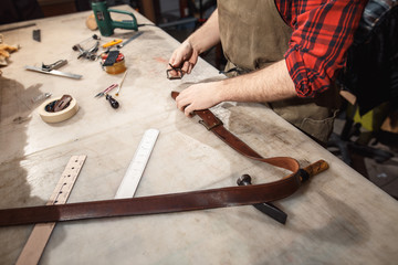 Close up of hands tanner performs work on table with tools