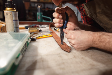 Close up of hands tanner performs work on table with tools
