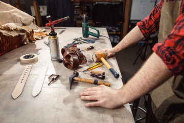 Close up of hands tanner performs work on table with tools