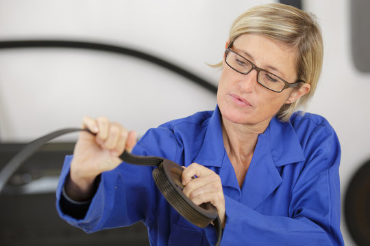 mature female mechanic working on auto part