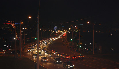 Road and cars with glowing headlight on background evening street. Intense vehicular traffic. Rapid night life of city.
