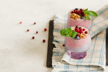 Layered chia, banana and berry smoothie garnished with fresh mint in purple glass