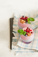 Layered chia, banana and berry smoothie garnished with fresh  mint, healthy food style on black slate background