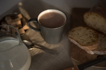 Mug of hot chocolate, milk and bread on a wooden background in the early morning