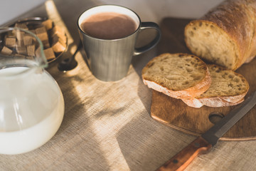 Mug of hot chocolate, milk and bread on a wooden background in the early morning