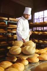 young cute baker smiling pulls out of the oven fresh bread shovel bread