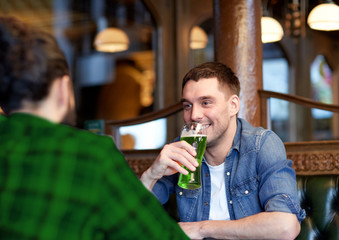 male friends drinking green beer at bar or pub