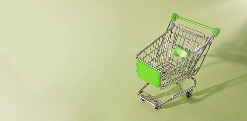 green trolley shopping chart on green background with lots of empty copy space