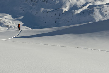 man practice ski mountaineering, high mountains, makes freeride skiing, backcountry, goes down in fresh snow, observes mountain, alone, isolated, lights, shadows, sunset, winter, Simplon Pass, Swiss
