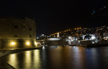 Fototapeta na wymiar Dubrovnik nochyu, view of the fortress and the city wall with reflection in the water