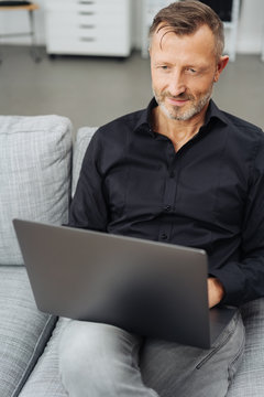 Man using a laptop on a sofa at home