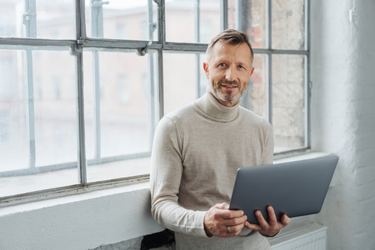 Man holding an open laptop looking at the camera