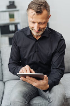 Smiling man using a tablet-pc at home on a sofa